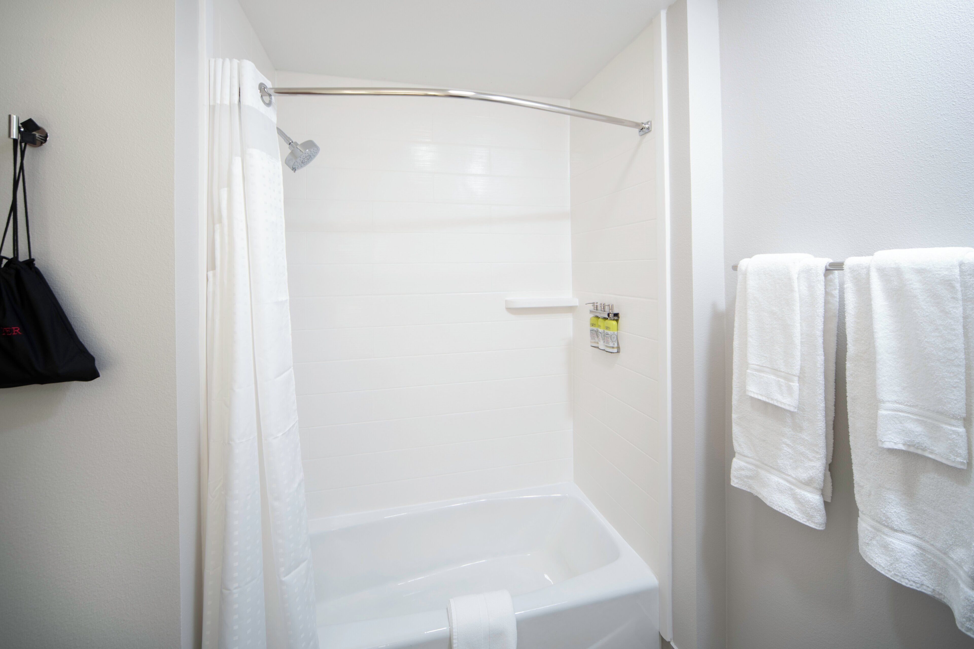 A bathroom with a shower, a toilet, and a towel rack with towels.