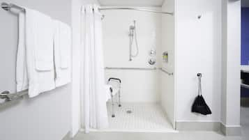 A modern bathroom with a shower, grab bars, a towel rack, and a black bag hanging on the wall.