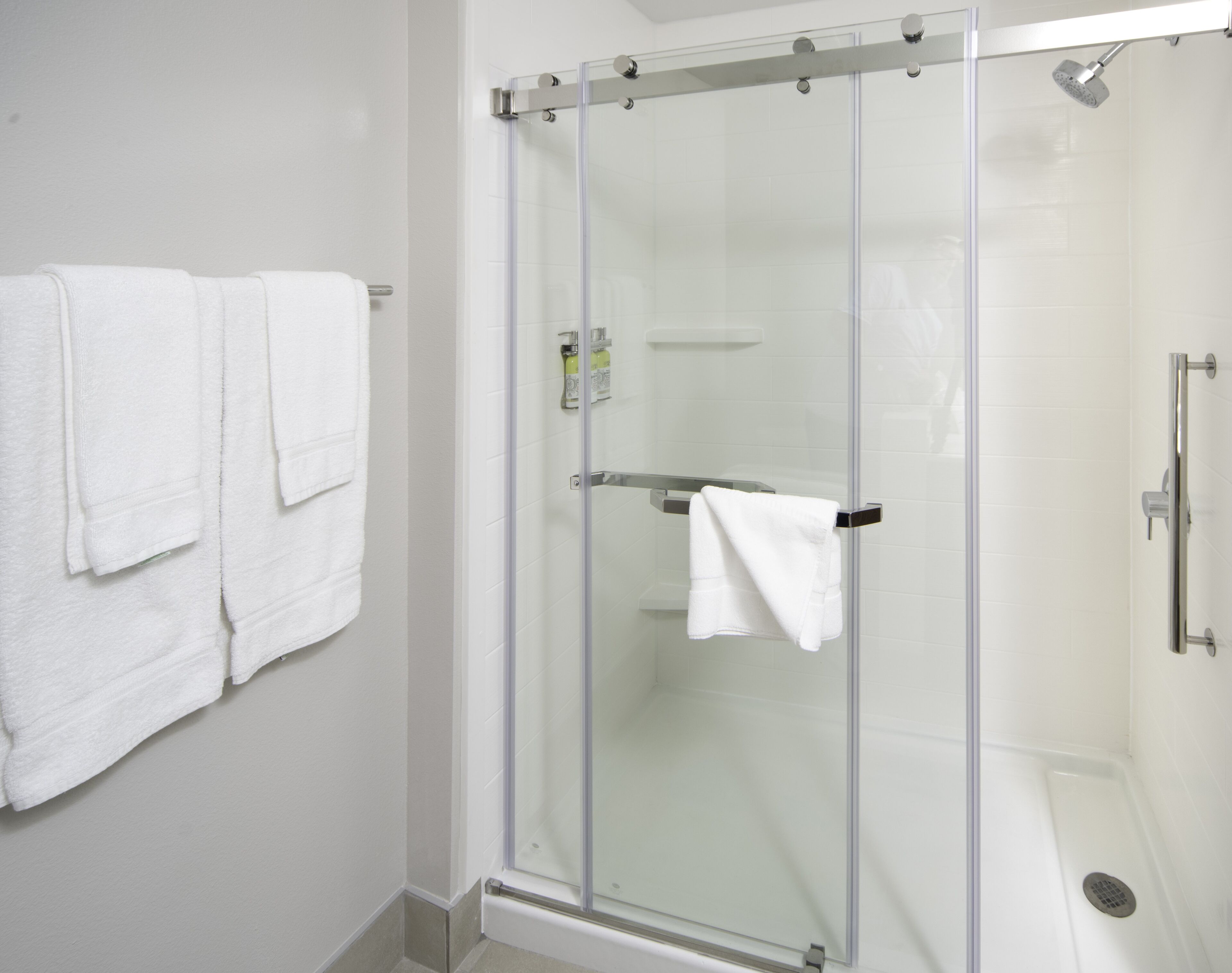 Um chuveiro com divisória de vidro, um porta-toalhas branco e uma toalha branca pendurada.