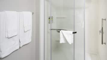 Um chuveiro com divisória de vidro, um porta-toalhas branco e uma toalha branca pendurada.
