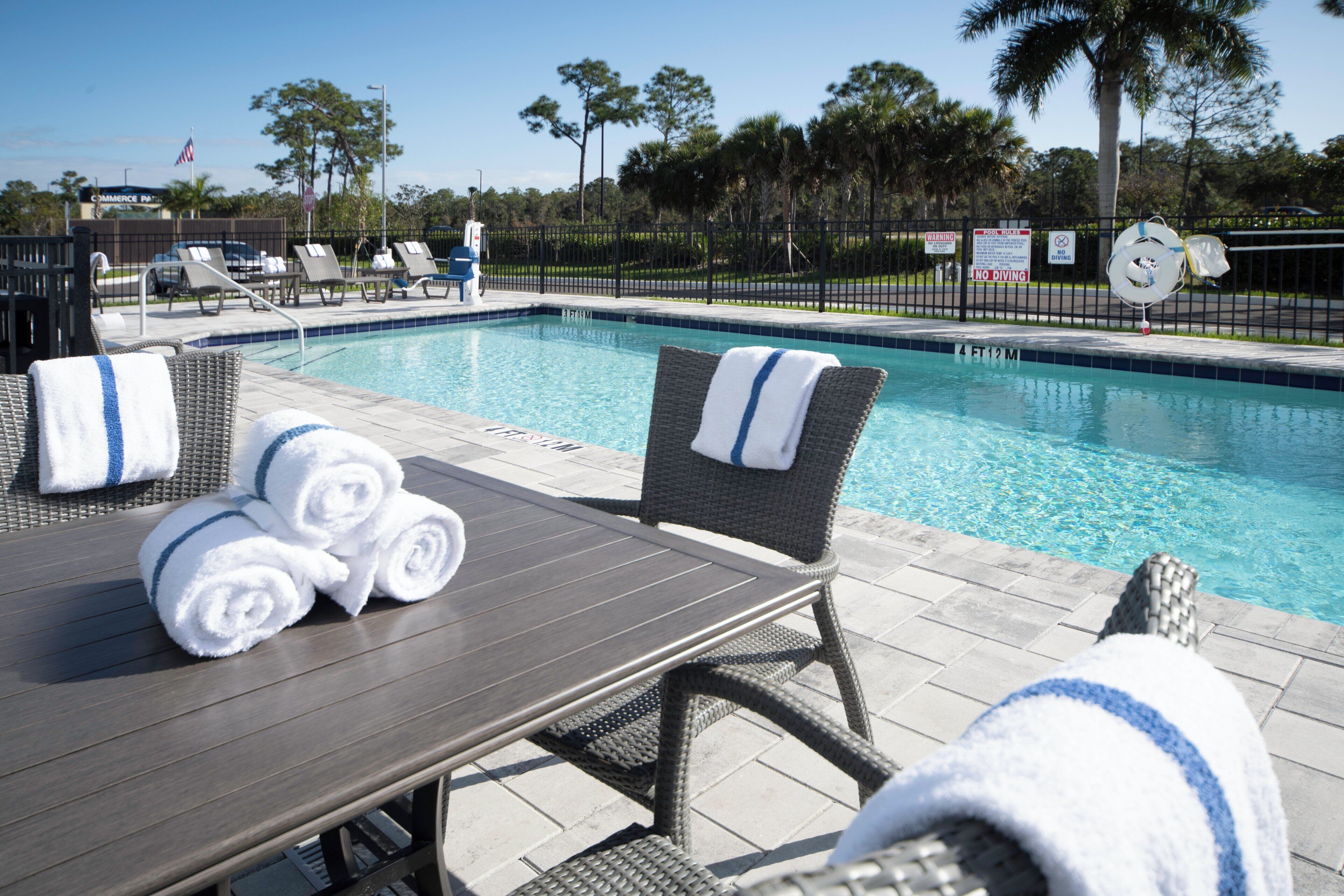 A poolside area with lounge chairs, a table, and towels.