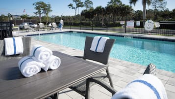 A poolside area with lounge chairs, a table, and towels.