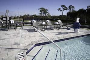 A poolside area with lounge chairs, a pool, and a fence. - Holiday Inn Express & Suites Fort Myers Airport by IHG (Fort Myers)