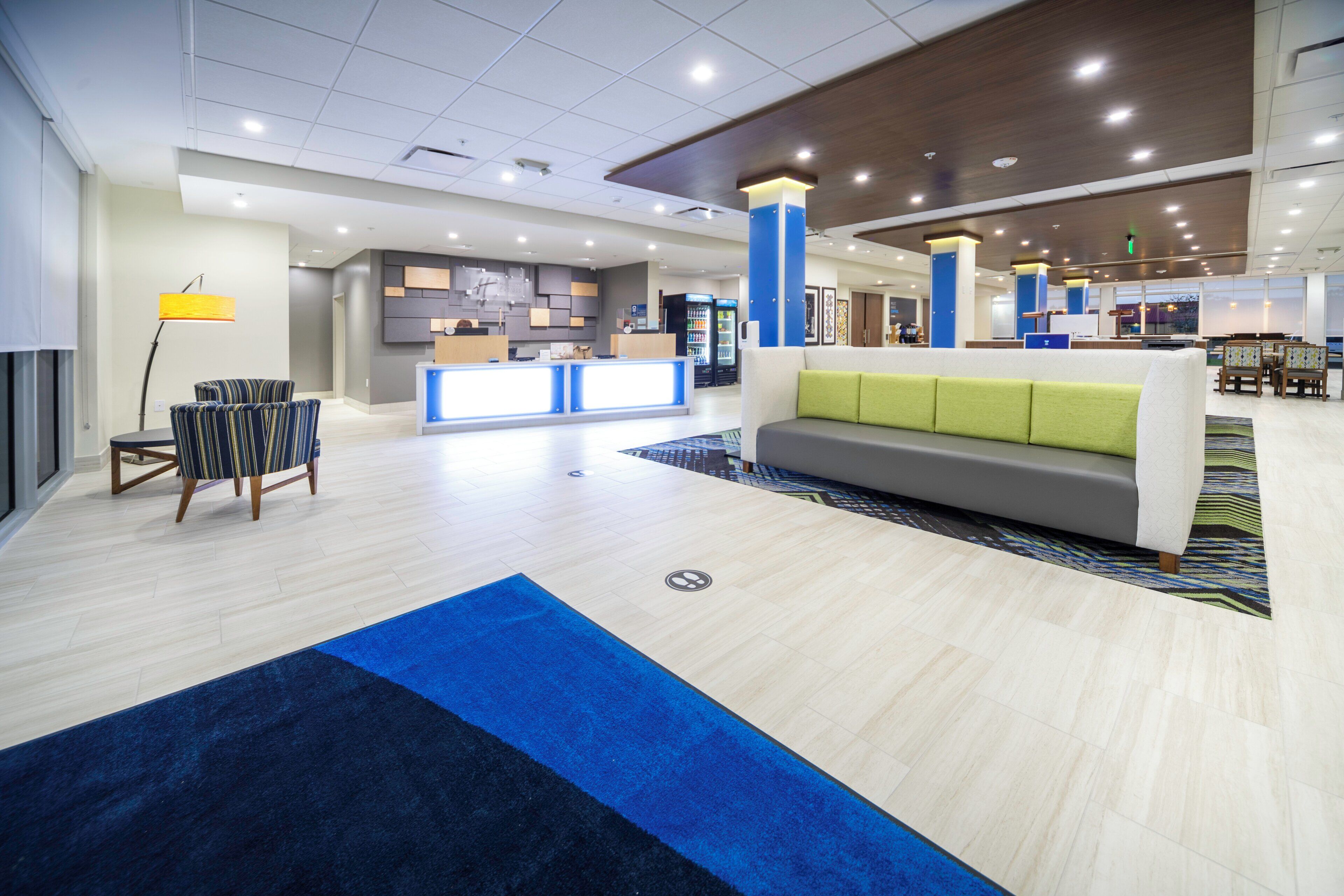 A modern hotel lobby with a reception desk, seating area, and a dining section.