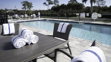 Una piscina al aire libre, sillones reclinables de piscina