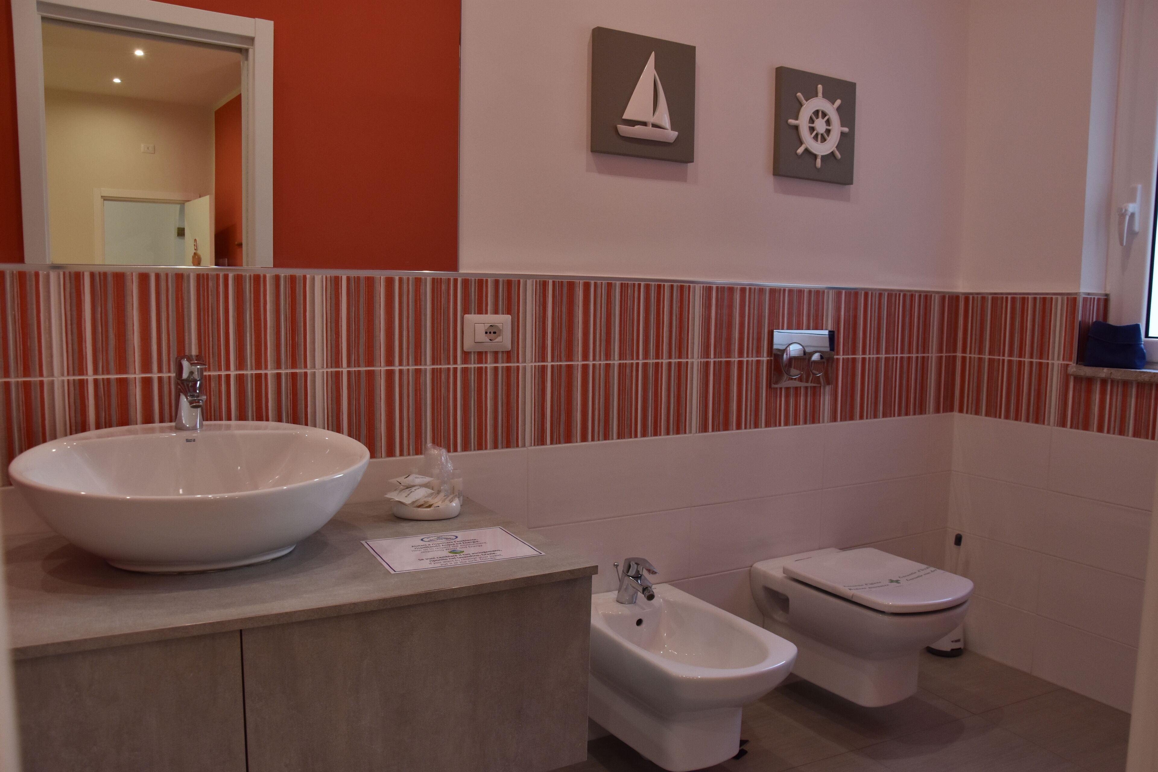 A bathroom with a large white sink, two toilets, and a bidet.