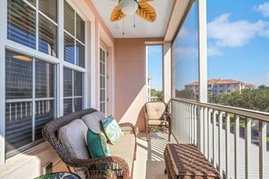 A balcony with wicker furniture, a ceiling fan, and a view of neighboring buildings. - South Fort Myers Gated Community! Heated Pool & Hot Tub! Close to Beaches, Shopping & Dining! (Fort Myers)