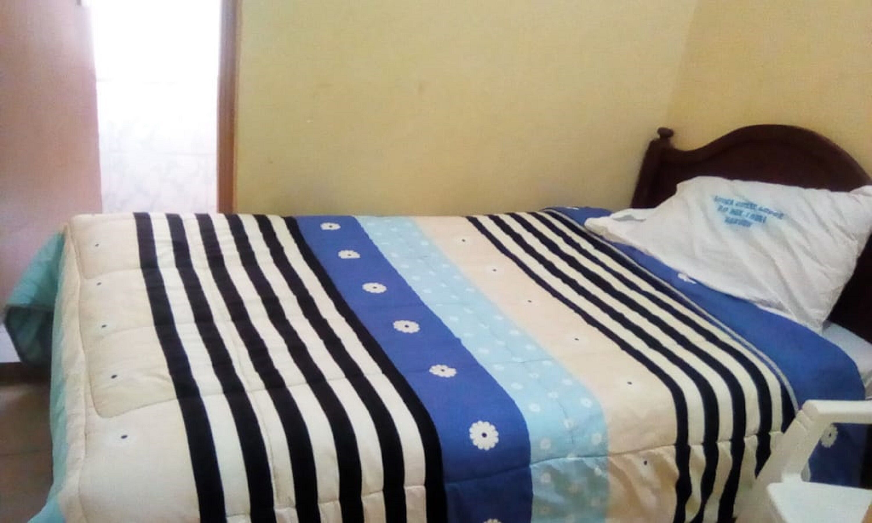 A bed with a striped bedspread and a pillow with text.