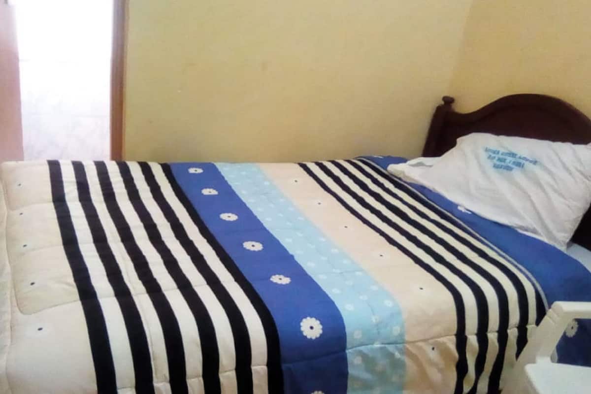 A bed with a striped bedspread and a pillow with text.
