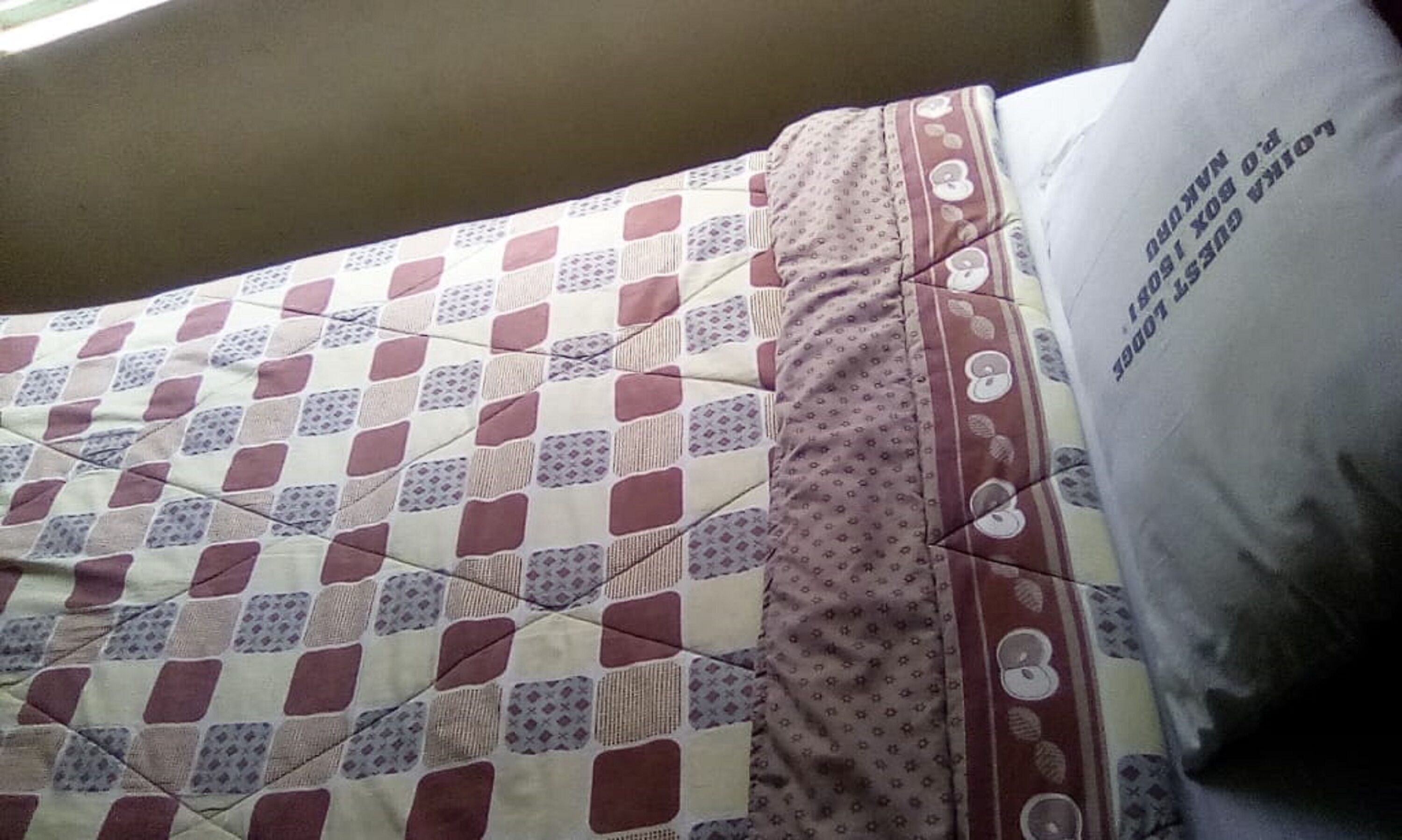 A bed with a quilt featuring a geometric pattern.