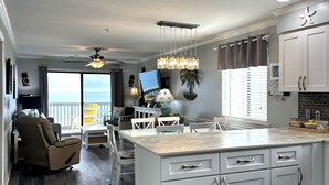A modern kitchen with white cabinetry, a large island, and a view of the ocean. - Sea Shadow 306 - Oceanfront in Surfside Beach (Surfside Beach)