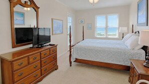 Une chambre à coucher comprenant un lit, une commode, un téléviseur, un ventilateur de plafond et une fenêtre donnant sur un paysage agréable.