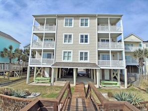 A multi-story residential building with balconies, a covered walkway, and outdoor seating.