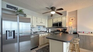 A modern kitchen with stainless steel appliances, a central island, and a ceiling fan. - Royal Garden Resort 811 - Oceanfront in Garden City Beach (Garden City)