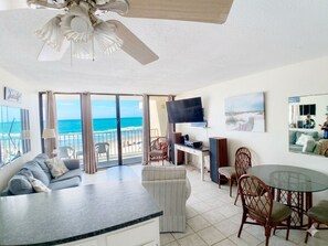 A living room with a sofa, a dining table, chairs, a TV, and a balcony with a view of the ocean. - Royal Garden Resort 214 - Oceanfront in Garden City Beach (Garden City)