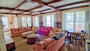 A spacious living room with a high ceiling, wooden beams, and large windows. - Second Creek - Oceanfront in Garden City Beach (Garden City)