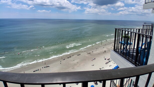 Un balcon avec vue sur la plage et l’océan.