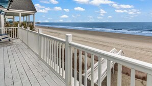 Une terrasse en bois avec des balustrades blanches donnant sur une plage.
