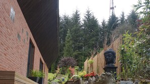 Una escalera de piedra conduce a un edificio de ladrillo con una terraza de madera y una estatua de Buda.