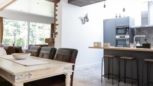 Una cocina moderna con una isla de madera, taburetes de bar y un área de comedor con mesa y sillas.