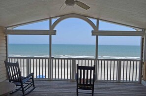 A covered porch with a view of the ocean, wooden railings, and two rocking chairs. - Seahorse Stables - Oceanfront in Surfside Beach (Surfside Beach)