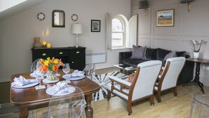 A dining area with a wooden table set for four, a black dresser, and a sofa.
