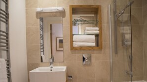 A bathroom with a sink, mirror, toilet, and shower.