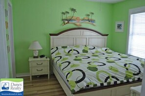 Ein Schlafzimmer mit einem Bett, einem Nachttisch, einer Lampe und einem Bild an der Wand.