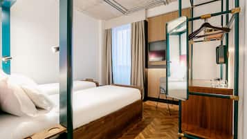 Una habitación de hotel con una cama de madera, un espejo, un armario y un perchero.