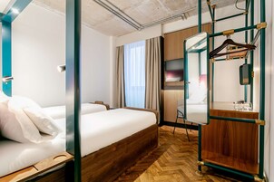 Una habitación de hotel con una cama de madera, un espejo, un armario y un perchero.