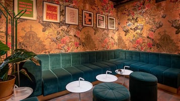 A green upholstered seating area with a mural, framed inspirational quotes, and a potted plant.