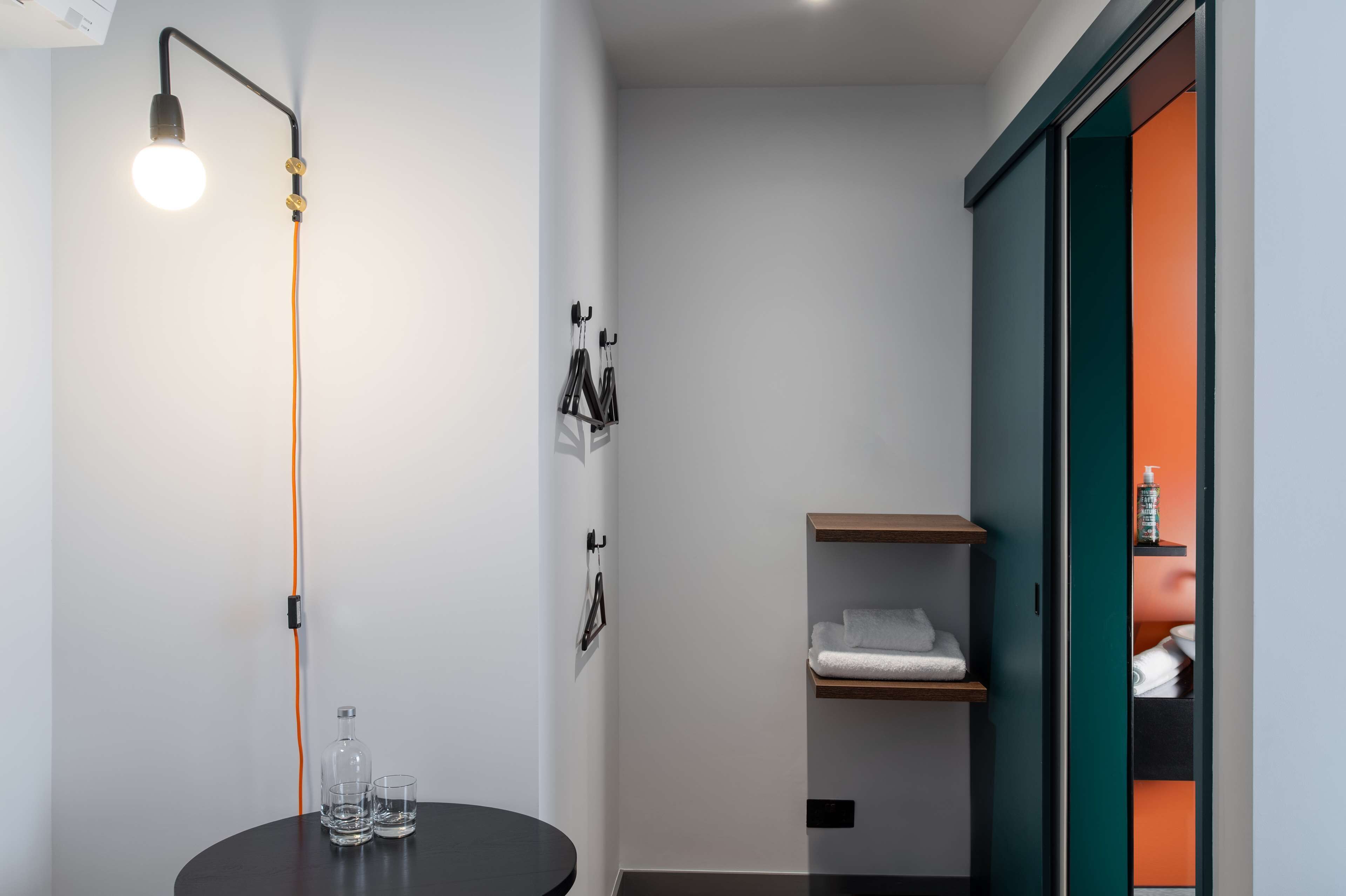 Ein modernes Zimmer mit einem runden Tisch, einer Stehlampe und einem Schrank mit einer türkisblauen Tür.