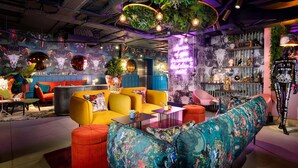 Un'area lounge vivace con sedute colorate, un neon e diversi elementi decorativi.