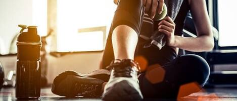 Una persona sentada en el suelo de un gimnasio, sosteniendo una toalla.