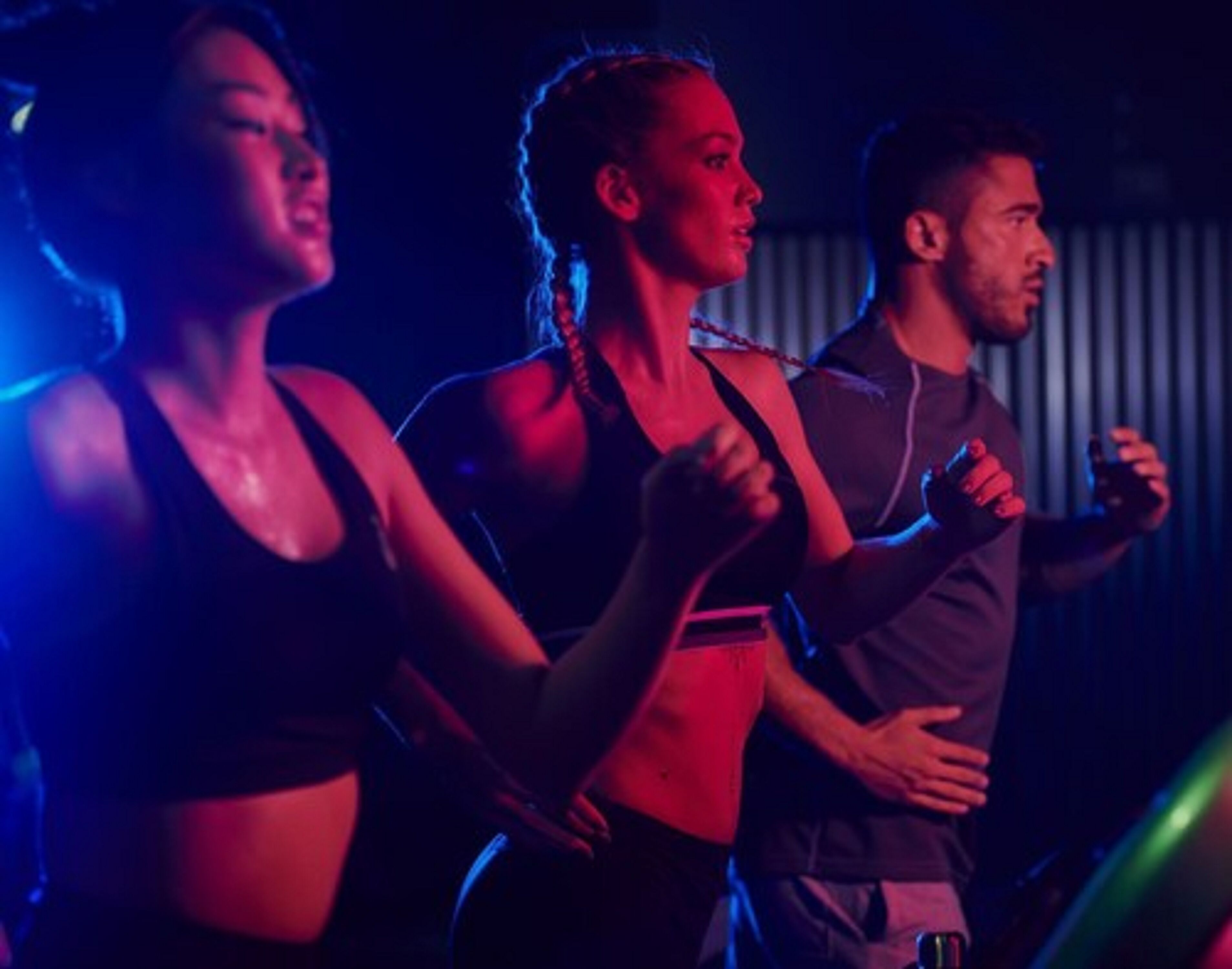 A group of people in a dimly lit room with red and blue lighting.
