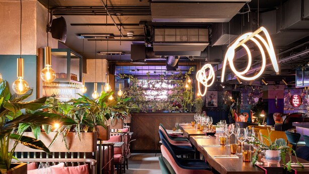 Un interno ristorante con banquette, tavoli, lampadari e un'area bar.