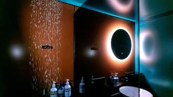 Experience a contemporary bathroom with a sleek design, featuring a large mirror, wall-mounted sink, and a vertical water feature.