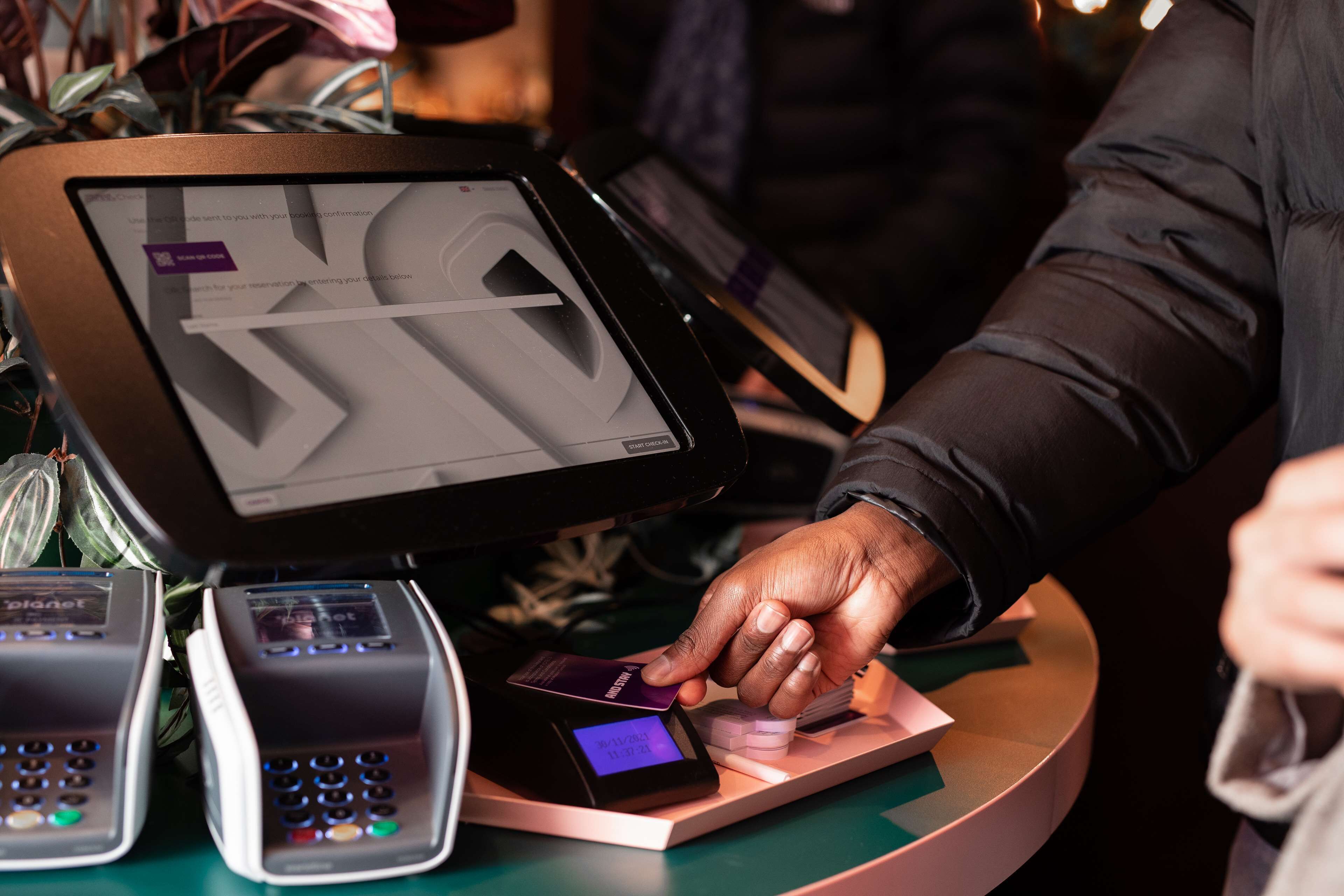 A person using a payment terminal at a counter.
