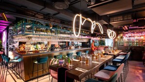 Un'area bar con un bancone, sgabelli da bar e una zona salotto con tavoli e sedie.