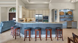 Una cocina amplia con una isla grande, electrodomésticos integrados y una zona de estar con taburetes de bar.