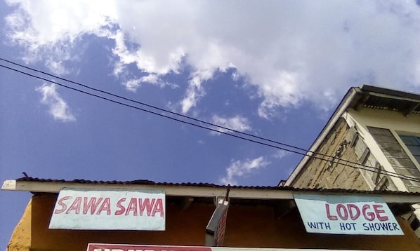 A building with signs for 'SAWA SAWA' and 'LODGUE WITH HOT SHOWER'.
