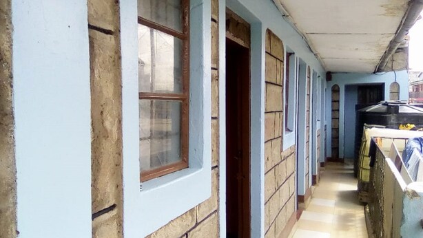 A narrow corridor with a tiled floor, a wooden door, and a window with a wooden frame. - Sawa Sawa Lodge - Adults Only (Nairobi)
