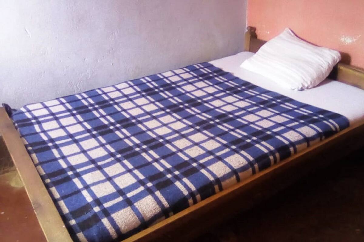 A single bed with a blue and white checkered bedspread and a white pillow.