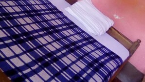 A single bed with a blue and white checkered bedspread and a white pillow. The room has pink walls and a wooden headboard. - Sawa Sawa Lodge - Adults Only (Nairobi)