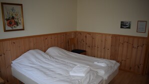 A single bed with white linens in a room with wooden paneling on the walls. - Skogmo Gjestgiveri (Overhalla)