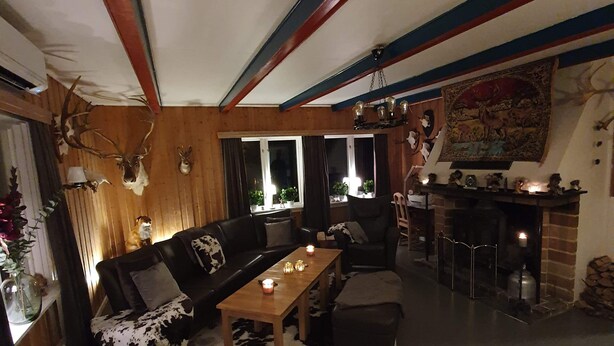 A cozy living room with a fireplace, wooden beams, and a sofa. - Skogmo Gjestgiveri (Overhalla)