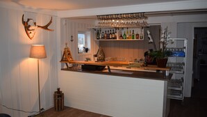 A bar area with shelves of bottles, glasses, and a potted plant. - Skogmo Gjestgiveri (Overhalla)