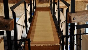 Eine schmale Holztreppe in einem rustikalen Dachzimmer mit freiliegenden Balken und Holzboden.