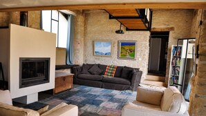 Ein gemütliches Wohnzimmer mit Kamin, einer Couch, einem Couchtisch und einem Bücherregal.