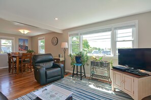 A living room with a dining area, a black leather chair, a television, and large windows. - Ryal Side Hideaway: Beverly Charm (Beverly)